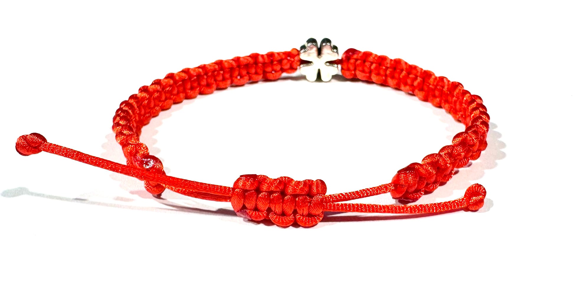 The Šnúrkový dámsky náramok štvorlístok červený features adjustable knots and a small silver four-leaf clover charm—a subtle talizman šťastia, beautifully presented on a white background.