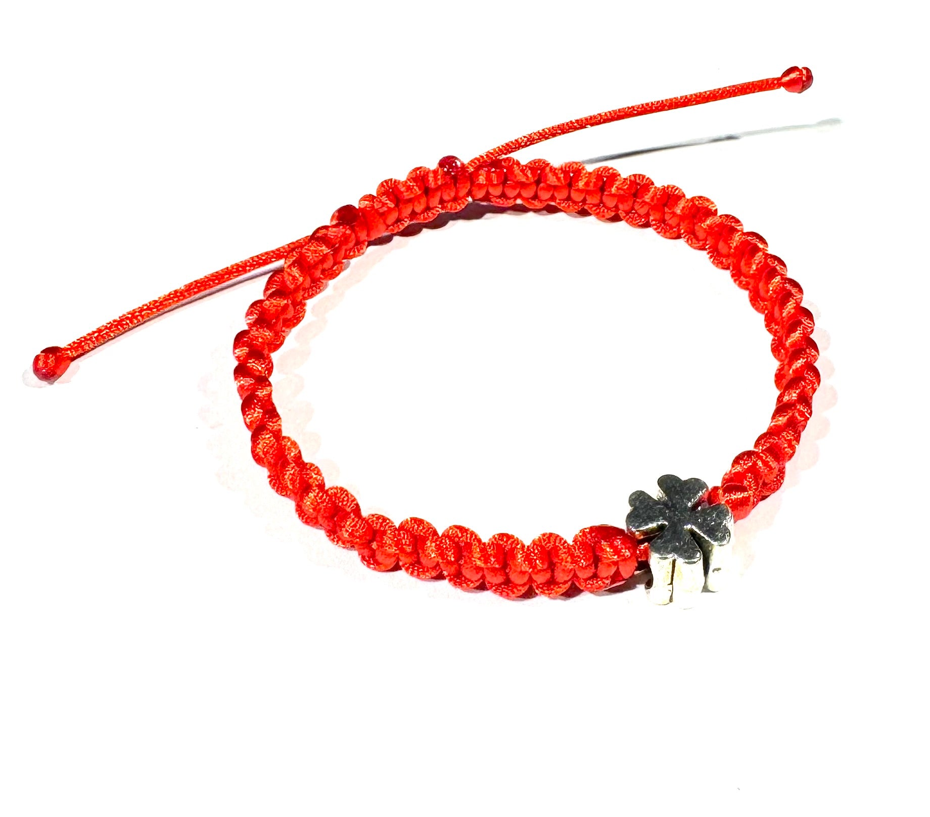 The Šnúrkový dámsky náramok štvorlístok červený is a red adjustable bracelet with a silver four-leaf clover charm, a simple talisman of luck, shown on a white background.